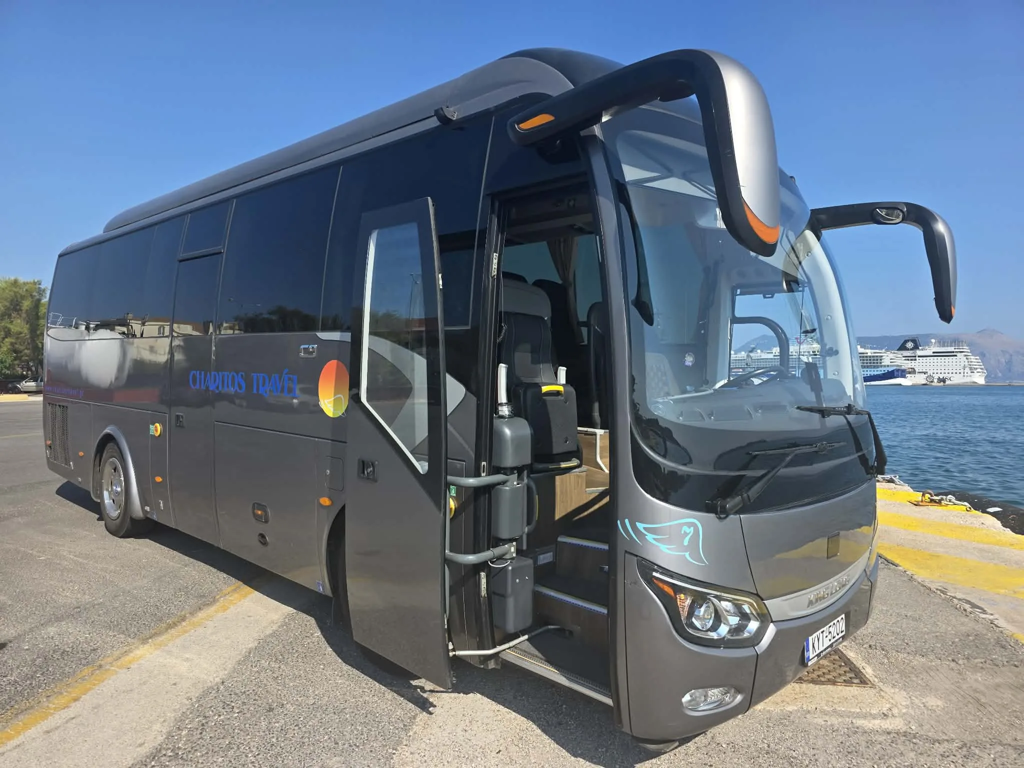 The 35-seat coach at Corfu cruise port with its door open, a cruise ship alongside